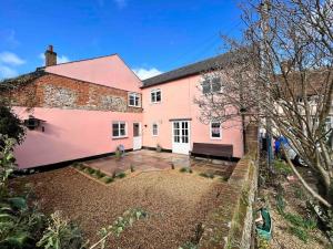 a pink house with a courtyard in front of it at Penny Black Cottage in Lavenham