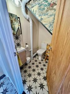 a bathroom with a staircase with a sink and a toilet at Penny Black Cottage in Lavenham