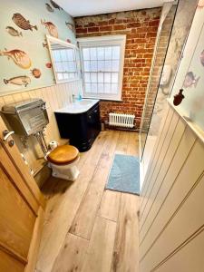 a bathroom with a toilet and a sink and a brick wall at Penny Black Cottage in Lavenham
