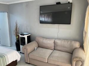 a living room with a couch and a flat screen tv at The Cottage in Rustenburg