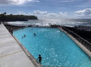 a group of people in a swimming pool next to the ocean at Ka Hema in Saint-Joseph
