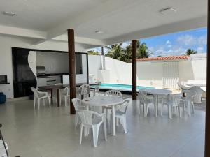 un patio con tavoli, sedie e piscina di Casa em FRENTE À PRAIA, ao lado do Nord Hotel - Tabatinga a Conde