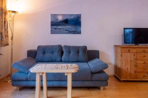 salon z niebieską kanapą i stołem w obiekcie Gästehaus Strauss w mieście Seefeld in Tirol