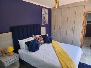 a bedroom with a bed with a blue headboard and pillows at SiBella guest house in Bloemfontein