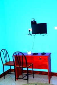 a red desk with two chairs and a tv on a blue wall at Safari Park House in Arusha