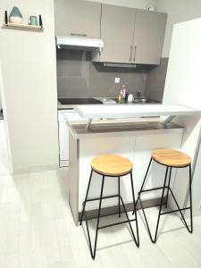 a kitchen with two bar stools and a counter at T2 plage de sable à 300m+ parking gratuit in Bandol
