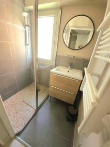 ein Bad mit einer Dusche, einem Waschbecken und einem Spiegel in der Unterkunft T2 plage de sable à 300m+ parking gratuit in Bandol
