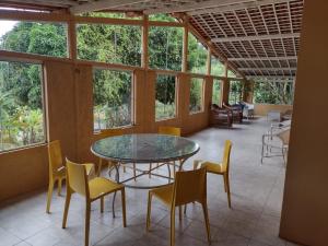 uma sala de jantar com uma mesa de vidro e cadeiras em CASA DA MONTANHA na Chácara Paraíso em Bananeiras
