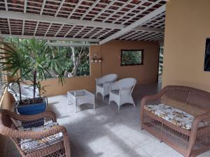porche con sillas de mimbre, sofá y mesa en CASA DA MONTANHA na Chácara Paraíso, en Bananeiras