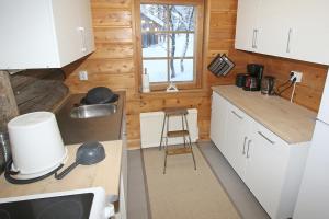 a small kitchen with white cabinets and a stool at Kuukkeli Log Houses Aurora Cabin - Jaspis in Saariselka