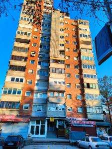 un edificio alto con coches estacionados frente a él en Jugi, en Novi Pazar