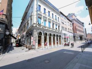 eine Stadtstraße mit Gebäuden und Menschen, die auf der Straße spazieren in der Unterkunft Le Royal Suites Sarajevo - City Center in Sarajevo