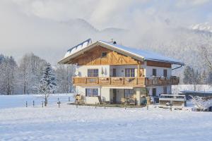een groot houten huis in de sneeuw met sneeuw bij Haus Moosmann am Sonnenplatz in Kössen