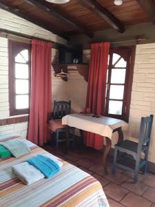 a bedroom with a bed and a table and two windows at La Tranquera Alquiler Temporario in Cafayate