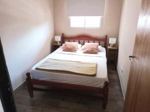 um quarto com uma cama com duas almofadas e uma janela em Cabañas La Fortaleza em La Caldera