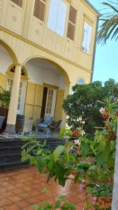 una casa amarilla con porche y algunas plantas en O Privilège Villa d'exception en Centre-ville de St-Pierre en San Pedro