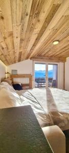 ein Schlafzimmer mit einem großen Bett und einem großen Fenster in der Unterkunft Attique - vue plongeante sur le lac de la Moubra in Crans-Montana