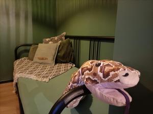 un dinosaurio de juguete de peluche sentado en una cama en SWANder, en Damme