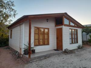 ein kleines weißes Haus mit einer Holztür in der Unterkunft Domos y cabañas Monte Patria in Monte Patria