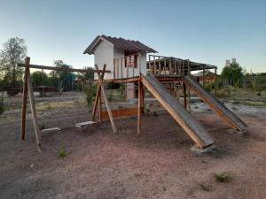 einen Spielplatz auf einem Feld mit einem Haus in der Unterkunft Domos y cabañas Monte Patria in Monte Patria