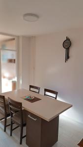 a dining room table with chairs and a clock on the wall at Opremljen stan na Alipašin Polju in Sarajevo