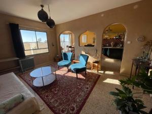 uma sala de estar com cadeiras azuis e uma mesa em The Flying Carpet - Crater Camel Mount View em Mitzpe Ramon