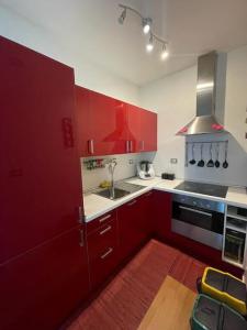 una cocina con armarios rojos y fregadero en Esclusivo loft con winter-garden, en Assago