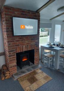 a brick fireplace with a television on top of it at The Gull & Puffin Cresswell in Cresswell