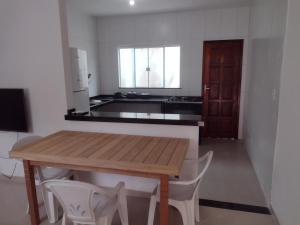 a kitchen with a wooden table and white chairs at Temporada Precisão Beta in Arraial do Cabo