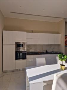 a kitchen with white cabinets and a white table at L'Elisir Home in Caserta