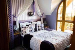 a bedroom with a bed with purple walls and a window at Karolowy Dwór in Wisła