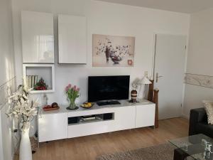 ein weißes Wohnzimmer mit einem Flachbild-TV in der Unterkunft Ferienvilla Waldstraße Wohnung Nr. 4 in Bansin