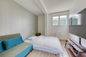 a bedroom with a bed and a couch and windows at Silver&Gold House Pro & Family in Ivry-sur-Seine