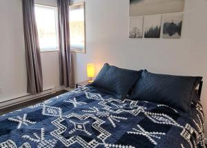 sypialnia z łóżkiem z niebieskim kocem i oknem w obiekcie Les Chalets Double K # 2 w mieście Saint-Alexis-des-Monts