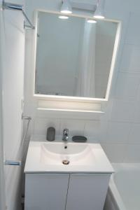 a white bathroom with a sink and a mirror at 2 pièces Port Cabourg - 2 à 4 personnes - 34 m2 - Balcon - Vue Port - Proche Plage in Dives-sur-Mer