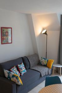 a living room with a blue couch with colorful pillows at 2 pièces Port Cabourg - 2 à 4 personnes - 34 m2 - Balcon - Vue Port - Proche Plage in Dives-sur-Mer