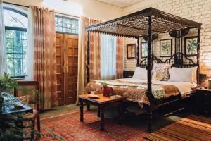 1 dormitorio con cama con dosel y mesa en Gorayya Villa, en Dehradun