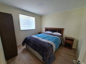 ein Schlafzimmer mit einem Bett mit einer blauen Decke und einem Fenster in der Unterkunft Cabaña en Bahía Murta, equipada para 4 personas in Bahía Murta