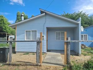 une petite maison blanche avec une clôture devant elle dans l'établissement Cabaña en Bahía Murta, equipada para 4 personas, à Bahía Murta