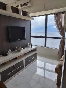 sala de estar con TV y ventana grande en Flat Tropical Executive en Manaos
