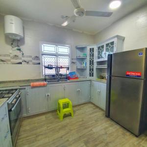 eine Küche mit einem Kühlschrank aus Edelstahl und einem gelben Stuhl in der Unterkunft alreaambreather2 in Sayq