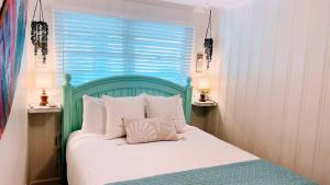 a bed with a green headboard in a room with a window at Seaward Escape - Cherry Grove Beach in Myrtle Beach