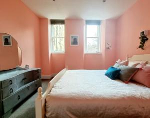 um quarto com paredes cor-de-rosa, uma cama e uma cómoda em Unique Victorian Home in Glasgow em Glasgow