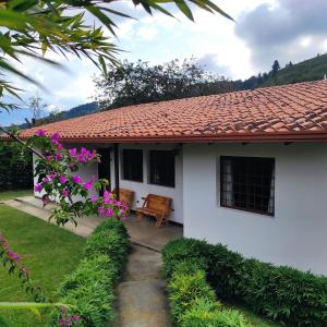 Biały dom z czerwonym dachem i fioletowymi kwiatami w obiekcie Casas Vacacionales La Cima w mieście Mérida