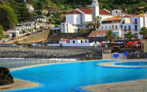 a view of a swimming pool with a town in the background at Apartamento T2-5m Aeroporto CR7 in Santa Cruz