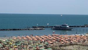 eine große Gruppe von Sonnenschirmen am Strand mit einem Boot in der Unterkunft Hotel Rosati in Rimini