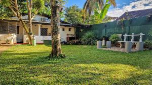 a park with a tree and a bench in a yard at Sun Set Sea Family House in Weligama