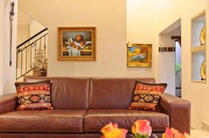 - un canapé en cuir brun dans le salon orné de peintures dans l'établissement Villa Toledo, à Pretoria