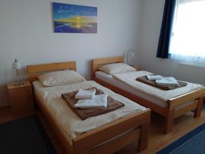 - 2 lits dans une chambre avec des serviettes dans l'établissement Apartman Braja, à Virovitica