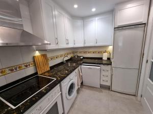 a kitchen with white cabinets and a sink and a refrigerator at FIRST Beach line in Marbella